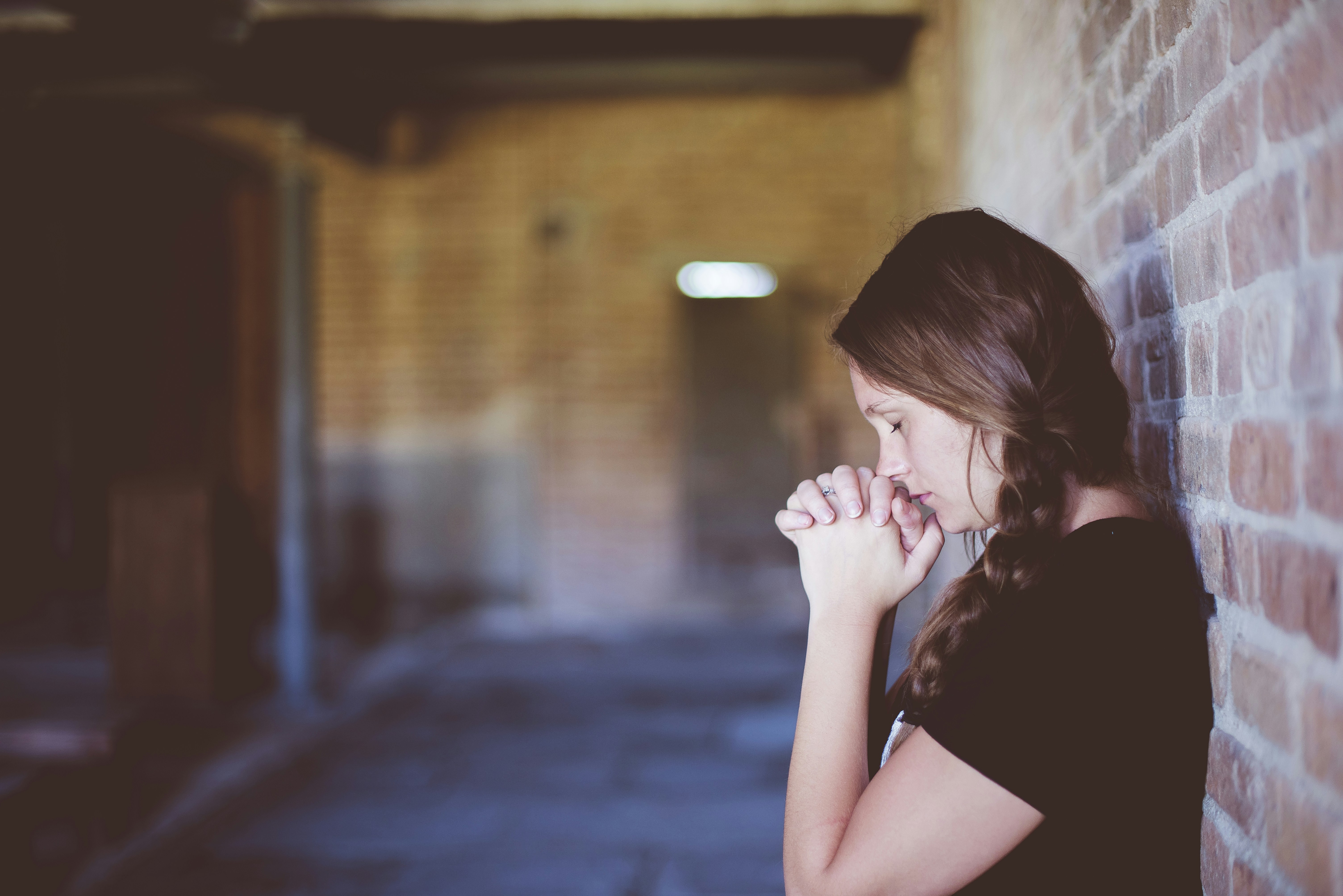 This picture is a woman with anxiety leaning against a wall thinking.